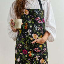 Load image into Gallery viewer, Person wearing a floral apron holding a mug against a plain background